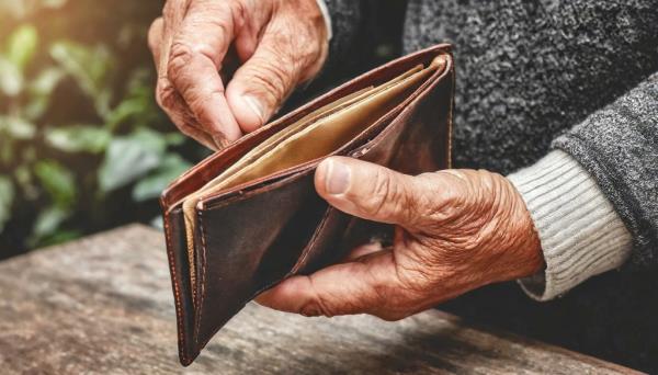 Old man opening an empty wallet, symbolizing poverty, high taxes or lack of savings